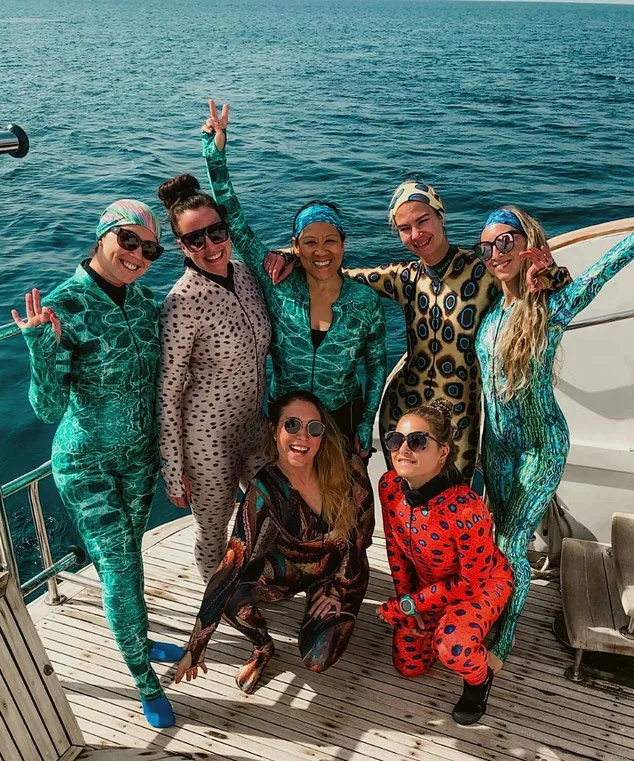 Group of women on the deck of a boat dressed in brightly coloured lycra suits for scuba diving