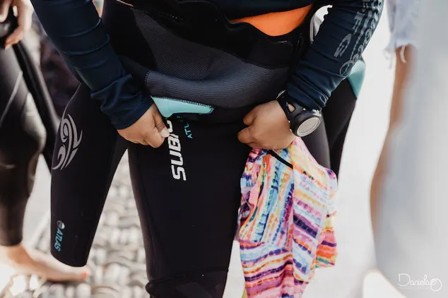 Woman pulling up a wetsuit whilst getting ready for scuba diving