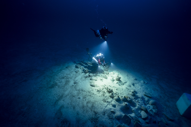 Scuba divers shining lights whilst recording a deep marine archaeological site in Malta