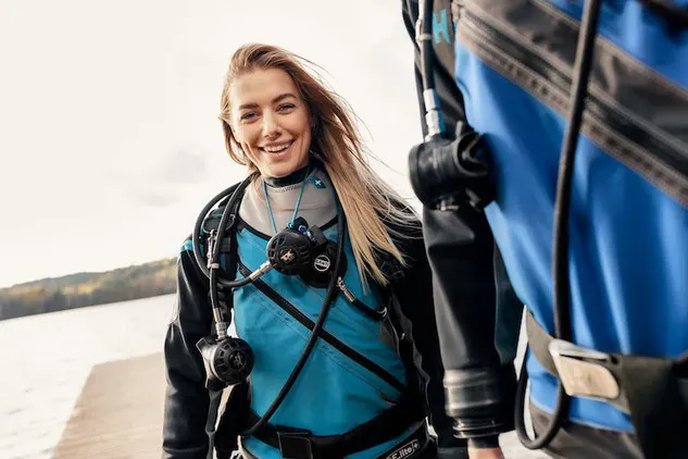 Woman preparing for scuba diving in a teal Santi drysuit