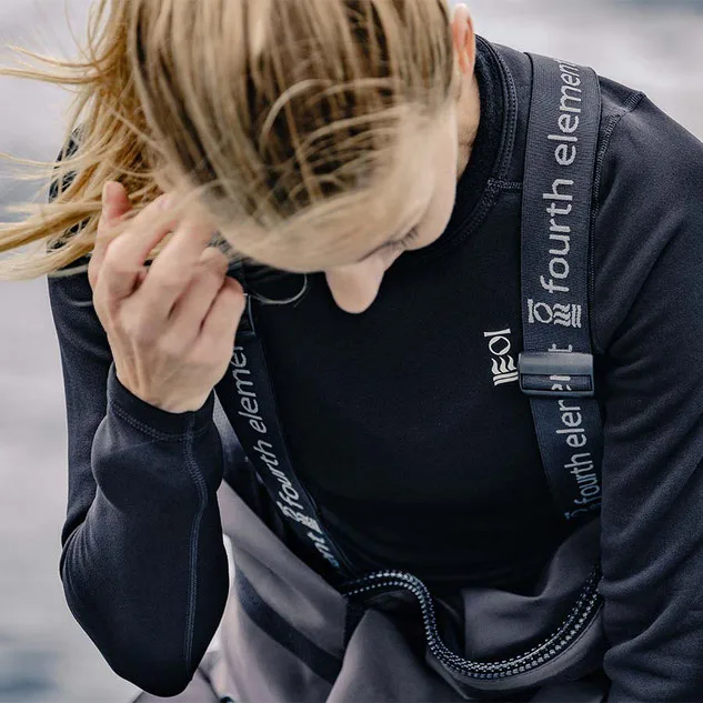 Woman scuba diver leaning forward wearing a black Fourth Element drysuit undergarment 