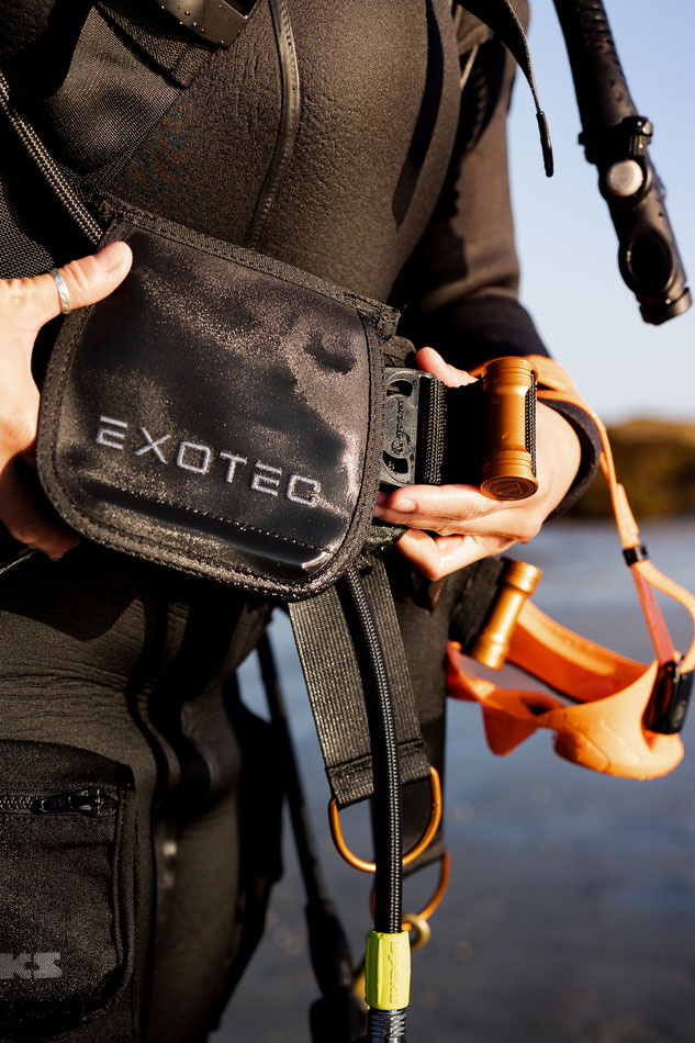 Close up of a woman's hands securing a weight pocket into the Apeks Exotec BCD