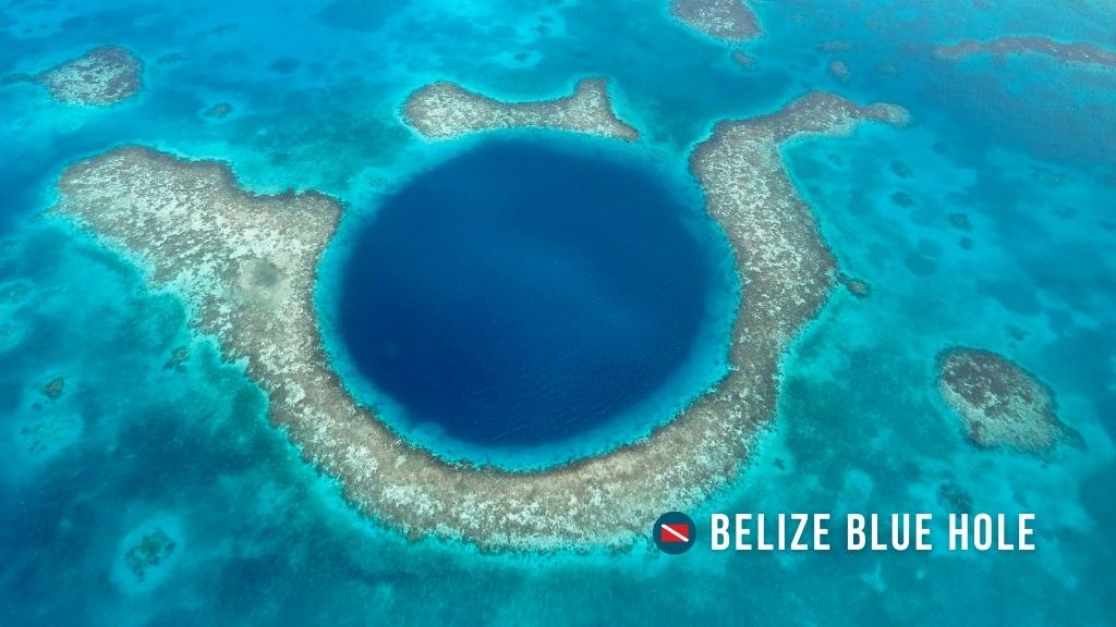 Aerial drone image of the blue hole in Belize. Turquoise waters and reef fringe the edges of a deep blue hole.
