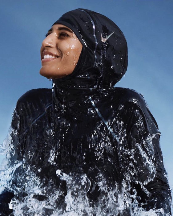 Girls that Scuba Ambassador Nouf smiles into the distance wearing a black swim hijab as she pushes herself out of the water
