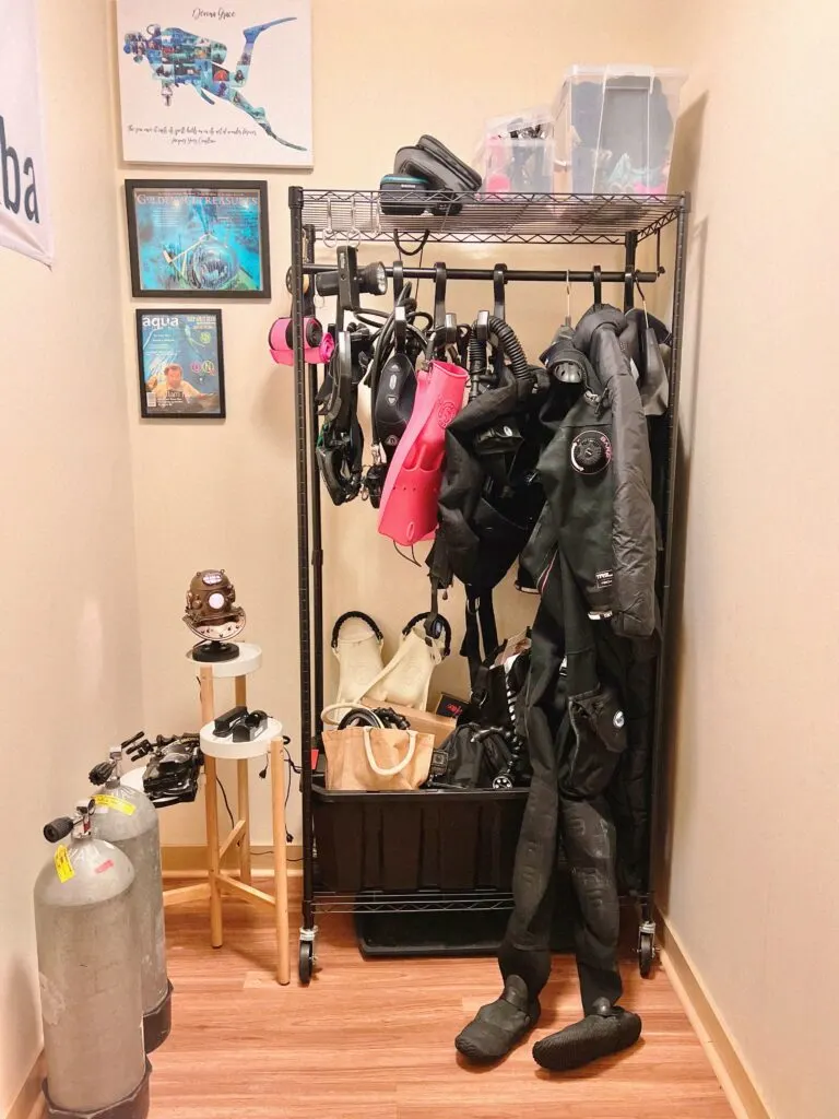 Scuba diving gear storage rack with equipment hanging, stored on shelf at the top, and in a box at the bottom.