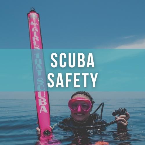 Woman scuba diver smiles at the camera, she is floating at the surface holding a bright pink delayed surface marker buoy which matches her bright pink mask, overlaid white text reads "SCUBA SAFETY"