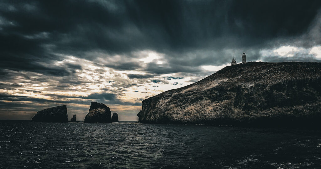 Islands of the Channel Islands National Park with a moody sky and a lighthouse.