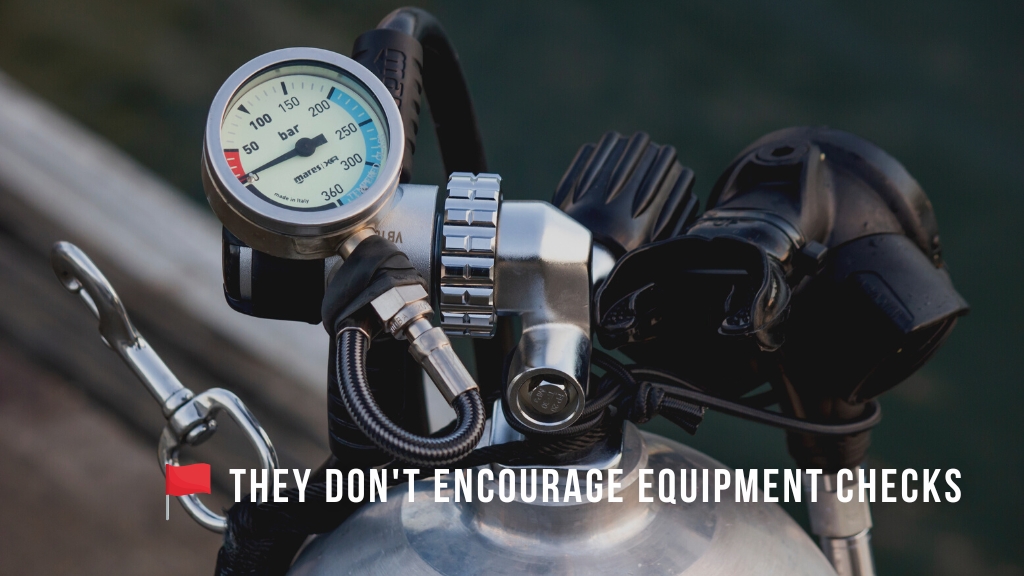 Close up of a scuba diving cylinder set up with regulators and a short pressure gauge. Overlaid white text reads "They don't encourage equipment checks" with a red flag icon. 