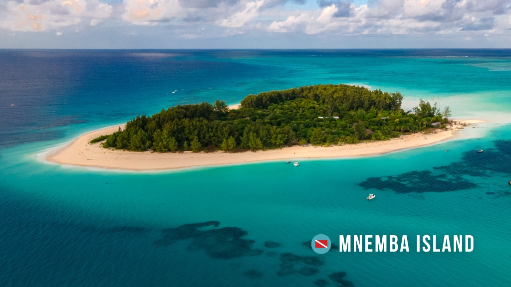 Aerial view of Mnemba Island, Zanzibar, a small island with lush green vegetation in bright turquoise waters.