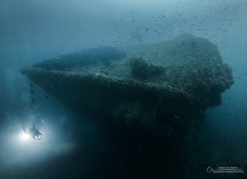 A diver swims to the left of the bow of the Franco wreck in Gallipoli, Turkey. Deep blue water surrounds the shipwreck. 