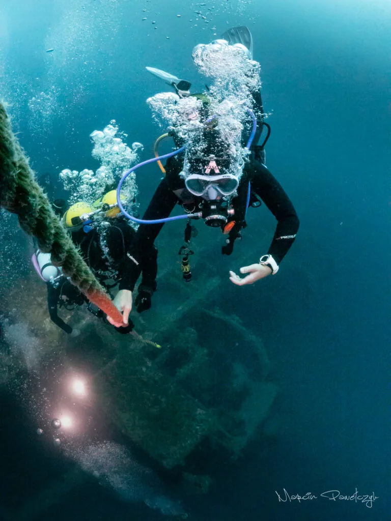 A woman scuba diver ascending up a line from a shipwreck. 