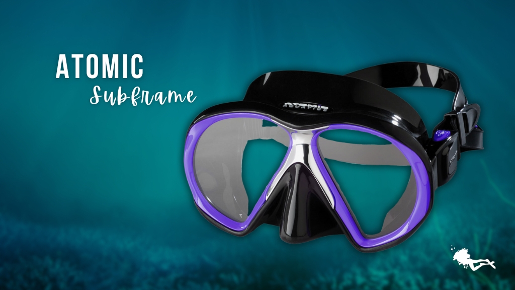 An Atomic Subframe women's scuba mask in purple and black against a blurred ocean background. 